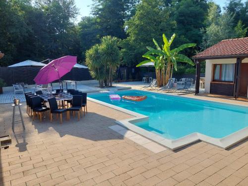 a swimming pool with a table and a purple umbrella at la dolce farniente in Biaudos