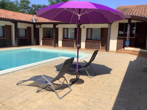 two chairs and a purple umbrella next to a pool at la dolce farniente in Biaudos