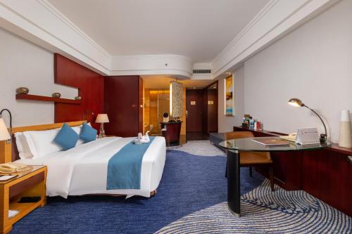 a hotel room with a large bed and a desk at Zhuhai Charming Holiday Hotel-Free Welcome Fruit Plate in Zhuhai
