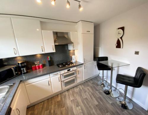 a kitchen with white cabinets and a counter with stools at NEW Super 2 Bedroom Flat in Falkirk in Falkirk