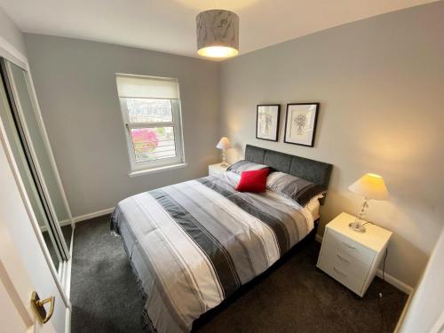 a bedroom with a bed with a red pillow and a window at NEW Super 2 Bedroom Flat in Falkirk in Falkirk