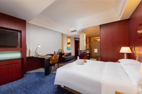a hotel room with a large white bed and a desk at Zhuhai Charming Holiday Hotel-Free Welcome Fruit Plate in Zhuhai