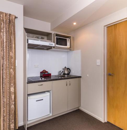 a small kitchen with a sink and a microwave at Twin Peaks Lakeside Inn in Taupo