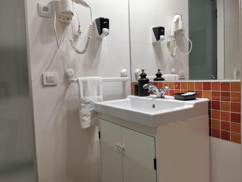 biała łazienka z umywalką i lustrem w obiekcie La Estancia de Leganitos w Madrycie