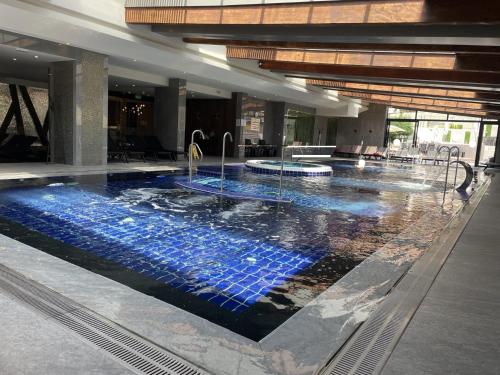 a large swimming pool with blue tiles in a building at Free SPA в Св. Иван Рилски - Сладък дом сред лукс in Bansko