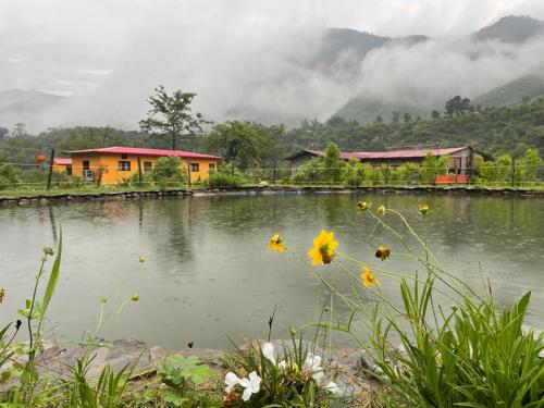 a house next to a body of water with buildings at Nayar Valley Retreat in Lansdowne
