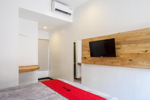 Klaten的住宿－RedDoorz @ Klaten City，一间卧室配有一张床,墙上设有一台平面电视