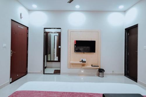 een grote witte kamer met een televisie aan de muur bij Bajaj's Karwan Inn in Jagdalpur