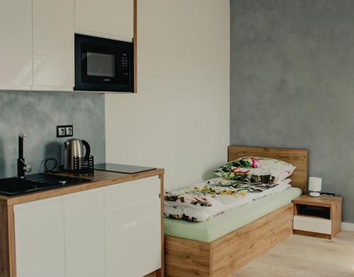 eine kleine Küche mit einem Bett und einer Mikrowelle in der Unterkunft Apartamenty Jordanów - Stacja Paliw MOYA in Jordanów
