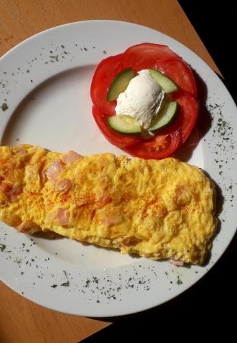 a plate with an omelet and a tomato and ice cream at Hotel Slodes in Belgrade