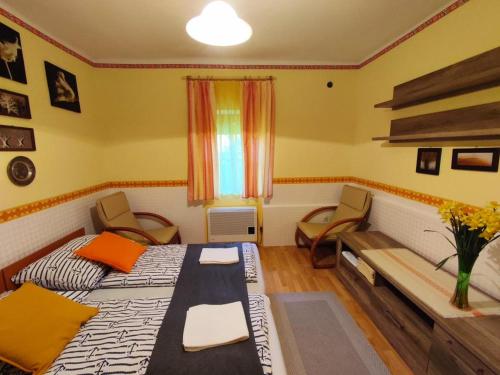 a bedroom with two beds and chairs and a window at Gábor apartmanok in Abádszalók