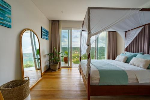 een slaapkamer met een hemelbed en een groot raam bij Villa Santosa Heights in Kuta Lombok