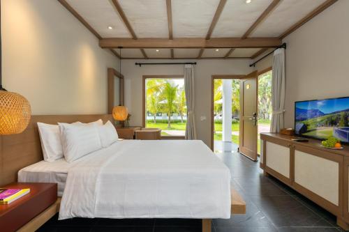 een slaapkamer met een groot wit bed en een televisie bij Coco Garden Resort in Phu Quoc