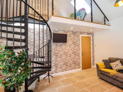 a spiral staircase in a living room with a brick wall at Glyndwr in Betws-y-coed