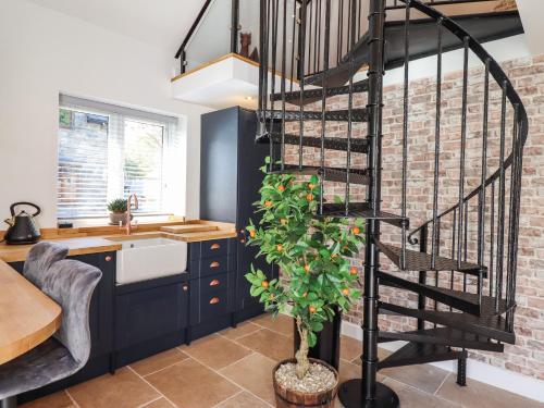 a spiral staircase in a kitchen with a brick wall at Glyndwr in Betws-y-coed