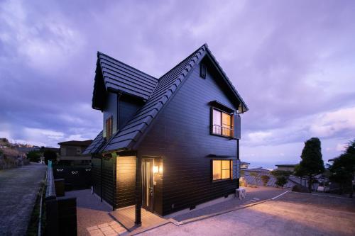 a black house with a dog standing in front of it at 別府温泉 小倉の湯 in Beppu