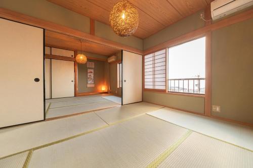 een lege kamer met ramen en een kroonluchter bij HAKUDAKU no YUYA in Beppu