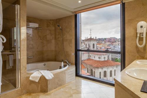 a bathroom with a tub and a large window at Hotel Bahía in Santander