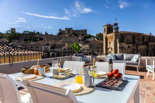 einen Tisch mit Speisen und Getränken auf dem Balkon in der Unterkunft Apartamentos El Patio, Plaza Mayor Trujillo in Trujillo