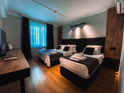 a hotel room with two beds and a desk at TEPE HOTEL&BUSINESS SUITE in Antalya