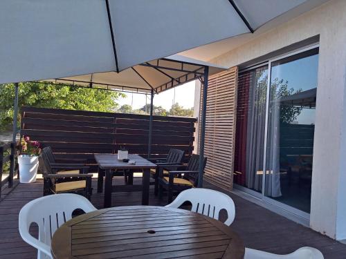 an outdoor patio with tables and chairs and an umbrella at ARIADNIS 3 BEDs apt in Pomos