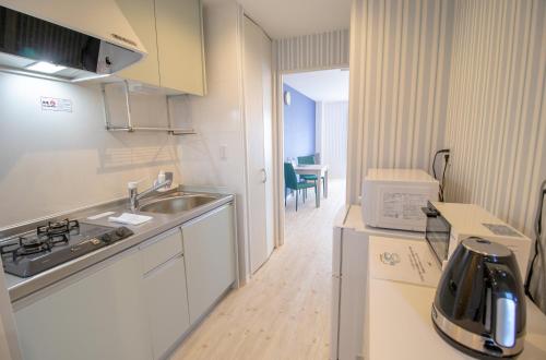 a kitchen with a sink and a counter with a microwave at Pine Hills Hotel Miyakojima in Miyako Island