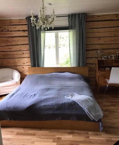 a bedroom with a bed with a chandelier and a window at Stor Familjegård i bra läge in Finström