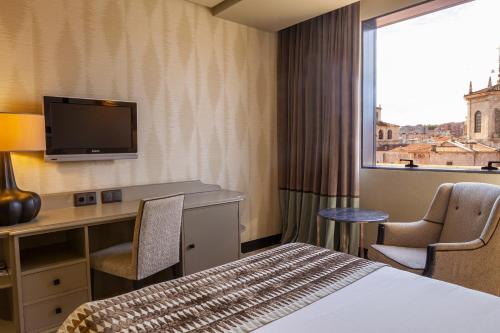 a hotel room with a bed and a desk and a window at Hotel Bahía in Santander