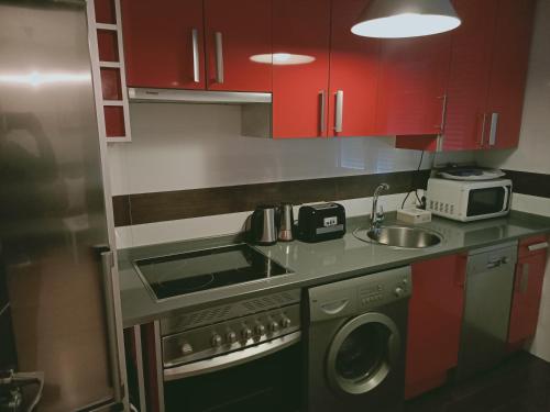a small kitchen with red cabinets and a sink at Ávila Flats Soterraña in Ávila