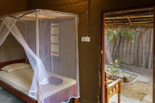 a bedroom with a canopy bed with a window at Little Bay Arugam Bay in Arugam Bay