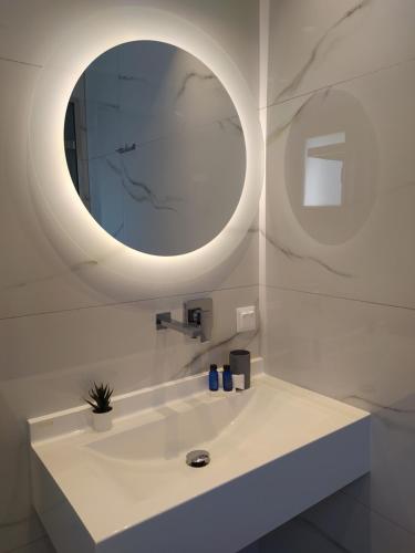 a bathroom with a white sink with a round mirror at Flâneur apartments in Ormos Panagias