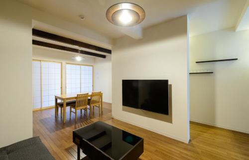 a living room with a table and a television on a wall at Shiki Homes KURUMI in Osaka