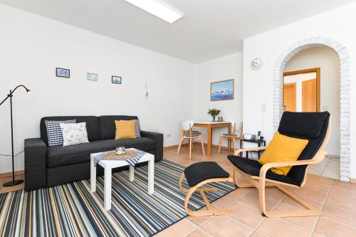 - un salon avec un canapé noir et des chaises dans l'établissement Ferienwohnung Nordseebutze, à Esens