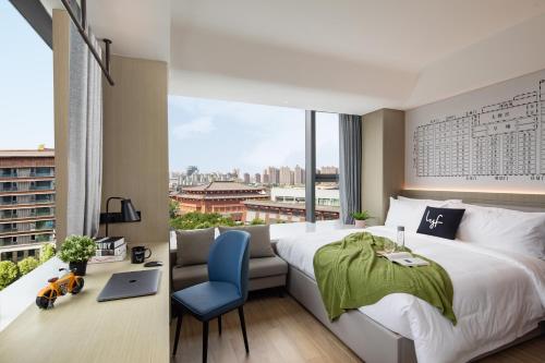 西安市にあるlyf Xi'an Dayanta by Ascott free gym & self-service free laundry roomのベッド、デスク、窓が備わるホテルルームです。