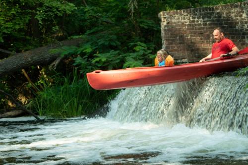 a man and a girl in a red canoe on a waterfall at Urzeka in Drzewce
