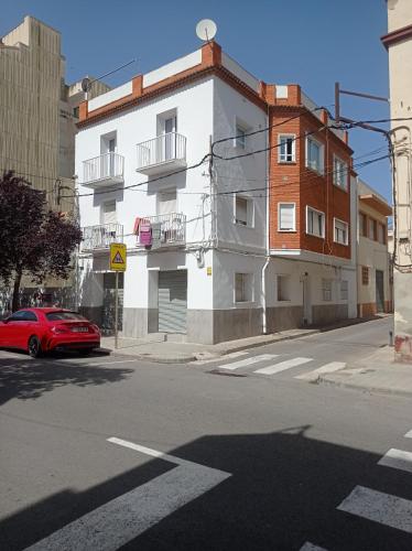 un coche rojo estacionado frente a un edificio blanco en Can Fabul, en Sant Carles de la Ràpita