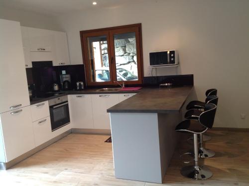- une cuisine avec un comptoir et quelques chaises dans l'établissement CHALET INDIVIDUEL TRES ENSOLEILLE AU CALME VUE IMPRENABLE, à Saint-Étienne-de-Tinée