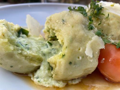 a plate of food with mashed potatoes and a tomato at Oleander Romantik Zimmer in Trausdorf