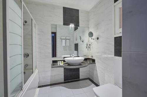 La salle de bains blanche est pourvue d'un lavabo et d'un miroir. dans l'établissement Golden Ocean Marina Hotel, à El Alamein