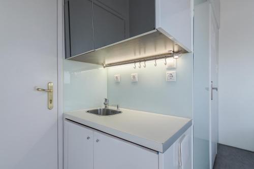 a white kitchen with a sink and a hood at Apartment With Terrace In Piraeus in Piraeus