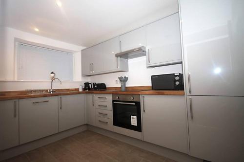 a kitchen with white cabinets and a sink at No 28D St Benedict in Glastonbury