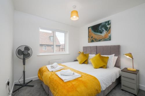 a bedroom with a bed with yellow sheets and a window at Modern 5 Bedroom 3 Bathroom Serviced House Aylesbury with parking By 360Stays in Aylesbury