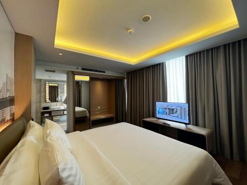 a hotel room with a bed and a television at Ra Suites Simatupang in Jakarta