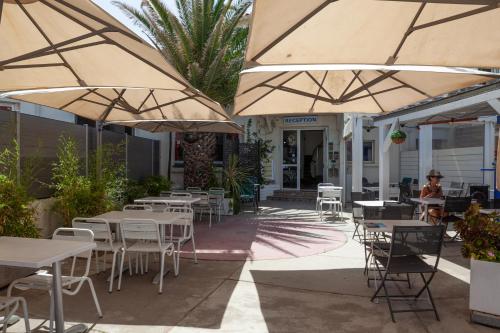 an outdoor patio with tables and chairs and umbrellas at Hotel La Casa in Le Barcarès