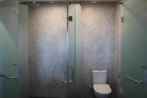 a bathroom with a toilet and a glass shower stall at Shakti Hotel Bandung in Bandung