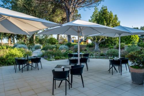 a patio with tables and chairs with umbrellas at Hotel Eden Park by Brava Hoteles in Riudellots de la Selva