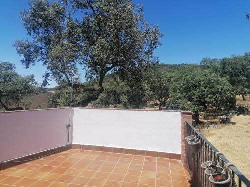 una cerca blanca de privacidad con un árbol en el fondo en Mirador de Jabuguillo, en Aracena