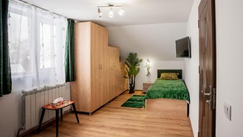 a bedroom with a green bed and a window at CASUTA CU FLORI in Vîlcele