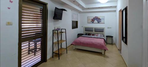 1 dormitorio con 1 cama con colcha rosa en 1351 דירת סטודיו עם מרפסת מול הים, en Bat Yam