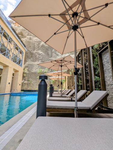 a group of chairs with umbrellas next to a pool at Citadines Abha in Abha